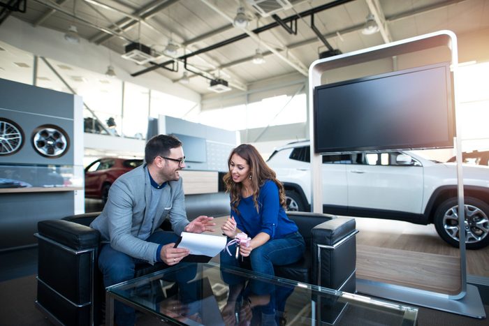 Salesperson meeting with a customer in a car dealership showroom